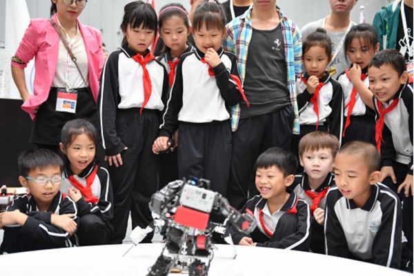 2018年10月,在第二十届中国机器人及人工智能大赛上,小观众被进行击剑比赛的仿人机器人吸引。新华社图